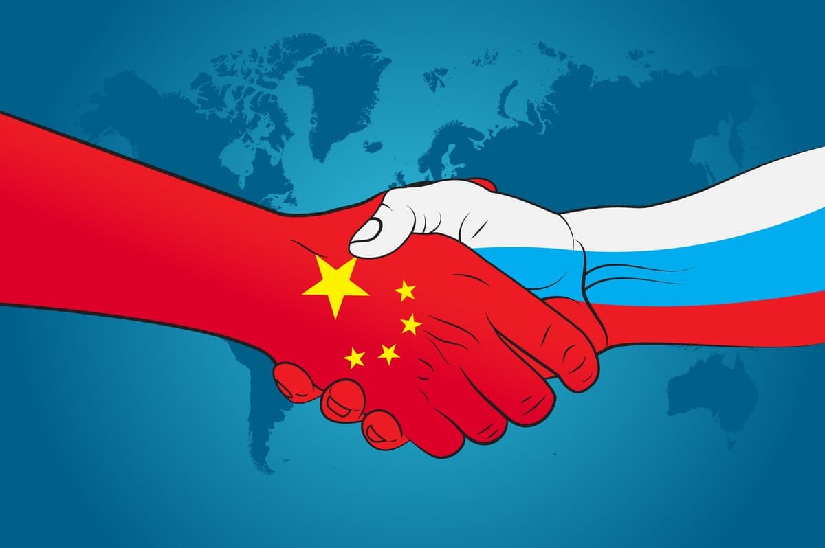 Иллюстрация сотрудничества России и Китая: рукопожатие на фоне флагов.